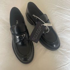 Product Code: 1d246m_uls_f0002_f_b050 Upper With Leather Strap Enameled Metal Triangle Logo 50 Mm Rubber Monobloc Sole With Hot-Stamped Logo Notched-Effect Stamped Rubber Welt Black Luxury Wingtip Loafers, Luxury Black Wingtip Loafers, Black Slip-on Calf Leather Oxfords, Luxury Black Loafers With Brogue Detailing, Black Platform Loafers With Brogue Detailing For Business, Luxury Black Slip-on Oxfords, Black Leather Platform Loafers For Business Casual, Black Calf Leather Loafers With Almond Toe, Designer Leather Loafers With Pointed Toe