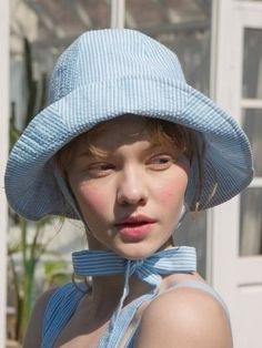 a woman wearing a blue hat with a tie around her neck