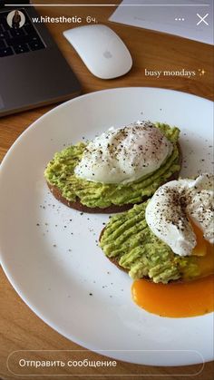 avocado toast topped with poached eggs on a white plate next to a laptop