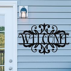 a welcome sign is hanging on the side of a house next to an open door