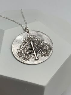 This unique tree of life handmade embossed oval round pendant has been entirely handmade using .999 fine silver. It has been cut from fine silver precious metal clay, textured, fired and oxidized. The pendant hangs from a sterling silver diamond cut cable chain. This fine silver pendant features an embossed tree of life on one side of the pendant and is reversible to a wood grain embossed pattern on the reverse side. Pendant size: approximately 1 x 1 1/4 inches Chain length: adjustable at 16 and Silver Engraved Nature-inspired Necklace, Silver Etched Nature-inspired Necklaces, Nature-inspired Sterling Silver Etched Jewelry, Nature-inspired Silver Etched Necklaces, Nature-inspired Etched Sterling Silver Jewelry, Nature-inspired Engraved Silver Jewelry, Nature-inspired Stamped Sterling Silver Jewelry, Nature-inspired Engraved Sterling Silver Necklace, Etched Silver Nature-inspired Jewelry