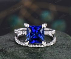 an engagement ring with a blue stone surrounded by white diamonds on top of a rock