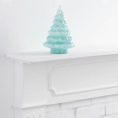 a blue glass christmas tree sitting on top of a white mantel above a fireplace