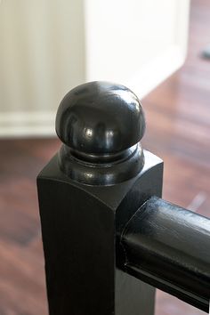 a close up of a black door handle with wood flooring in the back ground