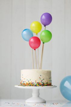 a birthday cake with colorful balloons on top by luma studio for stocksy photography