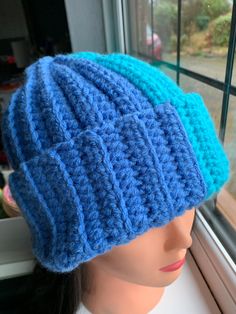 a crocheted blue hat sitting on top of a mannequin's head