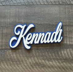 the word kenad written in blue and white on a wooden surface