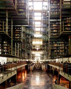 two people are standing in the middle of a large room with many bookshelves