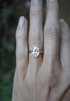 a woman's hand with a diamond ring on her left hand, showing the center stone