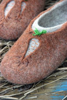 a pair of brown slippers sitting on top of dry grass