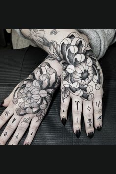 a woman's hands with tattoos and flowers on them