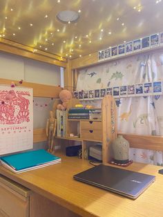 a desk with two laptops on it and a calendar hanging up against the wall