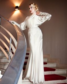 a woman in a white dress is standing on the stairs with her hands on her hips