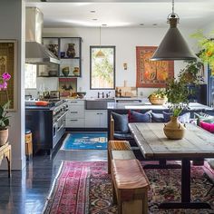 an open kitchen and dining room with rugs on the floor, potted plants in vases