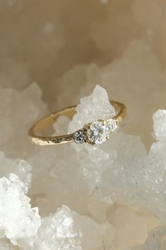 a gold ring with two diamonds on top of some ice crystals in front of it