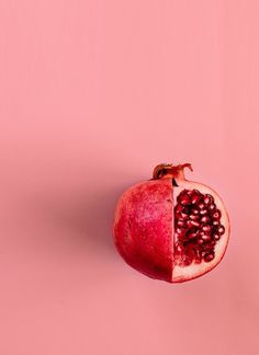 a pomegranate cut in half on a pink background