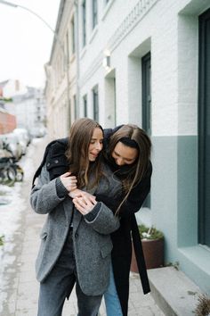 two women hugging each other on the sidewalk