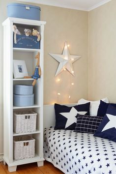 a white bookcase with blue and white stars on the wall next to a bed