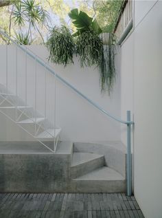 a set of stairs leading up to the second floor with plants hanging from it's railings