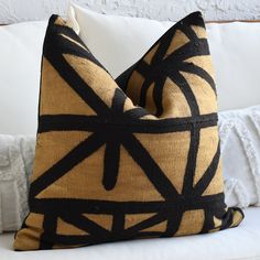 a black and gold pillow sitting on top of a white couch