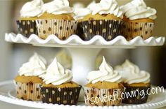 cupcakes with white frosting and brown polka dots on top are stacked on a cake plate