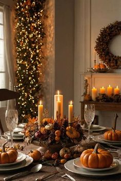 a dining room table set for thanksgiving dinner with candles and pumpkins in the center