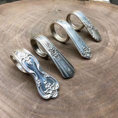 three silver rings sitting on top of a wooden table next to each other with designs