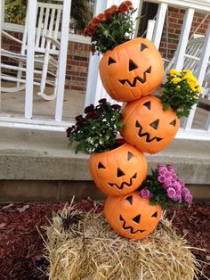 three pumpkins stacked on top of each other in front of a house with flowers