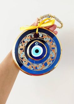 ⭐️Diameter of the blue evil eye bead is 14 cm(5.5 in) ⭐️Height of the blue eye wall charm is 28 cm(11 in) ⭐️Evil eye hanging is gold plated. There are two blue glass beads on the hanging. ⭐️Evil eye bead is painted. ⭐️ Evil Eye is totally handmade. ⭐️The evil eye bead is large and it is perfect for home decoration. ⭐️Turkish eye decor is also gold plated. It is believed that evil eye charm protects you from the evil eyes. Evil eye charm is over 5000 years old. It is found in all major religions Handmade Blue Evil Eye Bracelet For Festival, Bohemian Blue Evil Eye Bracelet For Festival, Traditional Blue Evil Eye Jewelry, Blue Evil Eye Bracelet For Festivals, Blue Evil Eye Bracelet With Round Beads For Festivals, Handmade Blue Jewelry For Blessing, Handmade Blue Evil Eye Bracelet For Good Luck, Evil Eye Hanging, Nazar Amulet