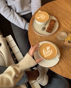 two people sitting at a table with cups of coffee