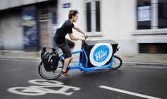 a man riding on the back of a blue bike with a bag strapped to it