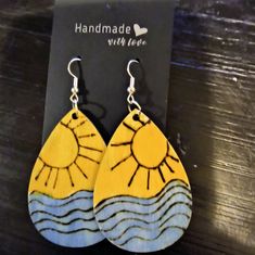 the earrings are made out of wood and painted with yellow, blue and white designs