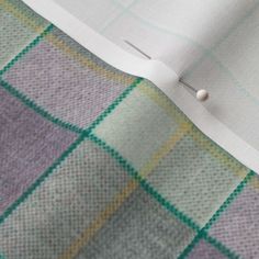 a piece of paper with some pins stuck to it's side on a plaid cloth