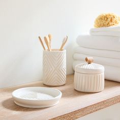 a white container sitting on top of a wooden table next to towels and a bowl