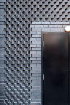 a black door in front of a brick wall with an intricate design on it's side