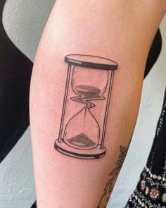 a woman's arm with an hourglass tattoo on it