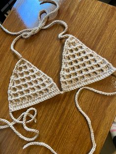 two crocheted triangle shaped objects sitting on top of a wooden table