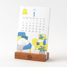 a desk calendar with an image of a cat sleeping on a chair in front of a table