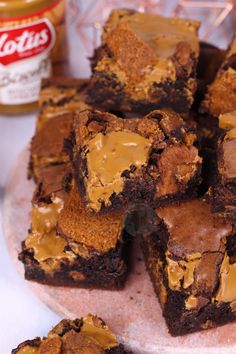 brownies with peanut butter frosting on a plate next to jars of peanut butter