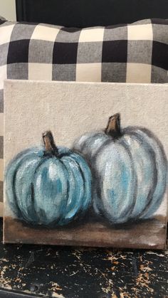 two blue pumpkins sitting on top of a table next to a black and white checkered pillow