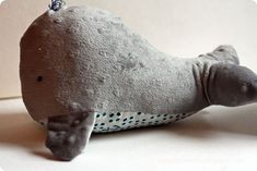 a gray stuffed animal laying on top of a white table next to a black and blue polka dot pillow