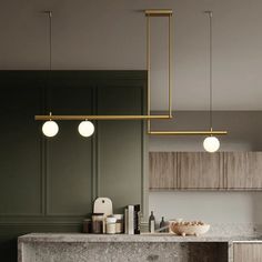 a kitchen with marble counter tops and green cabinets, hanging lights over the island area