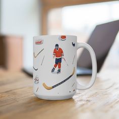 a white coffee mug with an image of a hockey player on it sitting in front of a laptop