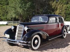 an old fashioned car parked in the dirt