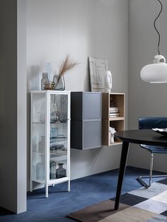 a room with a table, chair and shelf in the corner next to a window