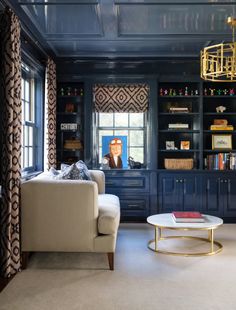 a living room filled with furniture and bookshelves next to a window covered in curtains