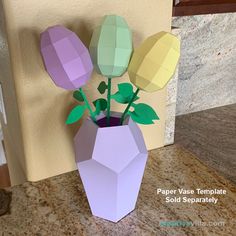 a paper vase with flowers in it sitting on a counter top next to a wall