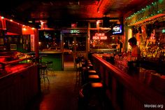 a dimly lit bar with neon lights in the background