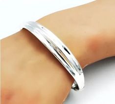 Elevate your jewelry collection with this exquisite Sterling Silver Bangle Bracelet. Crafted from premium 925 sterling silver, this elegant piece boasts a rolling, spring-hinged design that provides both comfort and style. Its lightweight construction ensures ease of wear throughout the day. The bracelet measures 6.5 inches (16.5 cm) in inside circumference, making it an ideal fit for many. Each bracelet is stamped with "925," signifying its authenticity and high-quality composition. The hollow Classic 925 Stamped Bangle For Anniversary, Classic Sterling Silver Bangle For Anniversary, Sterling Silver Bracelet With Shiny Finish For Anniversary, Anniversary Sterling Silver Bracelet With Shiny Finish, Sterling Silver Bracelet With Shiny Finish For Formal Occasions, Classic 925 Stamped Cuff Bracelet For Anniversary, Formal Adjustable Sterling Silver Bracelet With Shiny Finish, Classic Adjustable Sterling Silver Bracelet With Shiny Finish, Sterling Silver Bangle With Shiny Finish For Anniversary