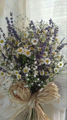 a bouquet of wildflowers tied to a burlock on a window sill